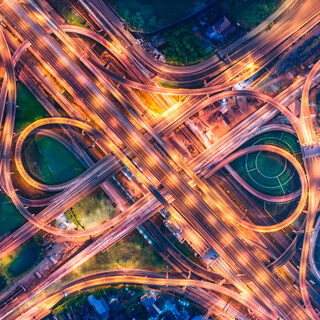 Aerial view over complicate intersection road and express way in Bangkok Thailand at night with long exposure vehicle light trail. Shot by drone.